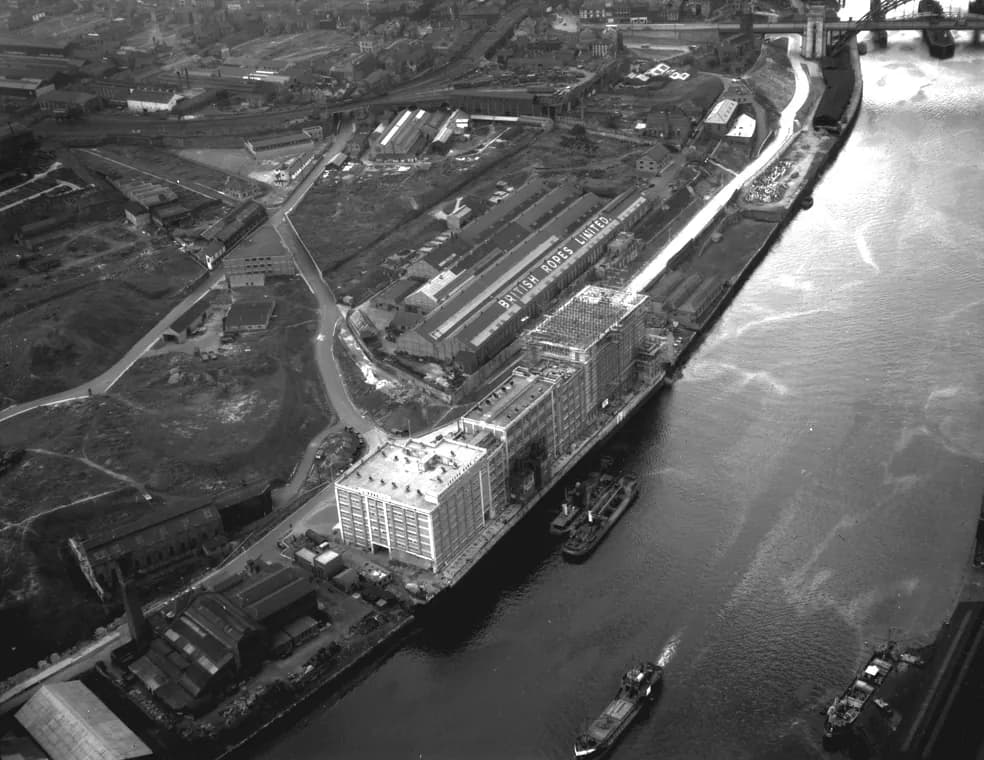 Aerial view of the new Baltic Flour Mills on the Gateshead bank of the Tyne, with warehouses, rail lines and a ship on the river.