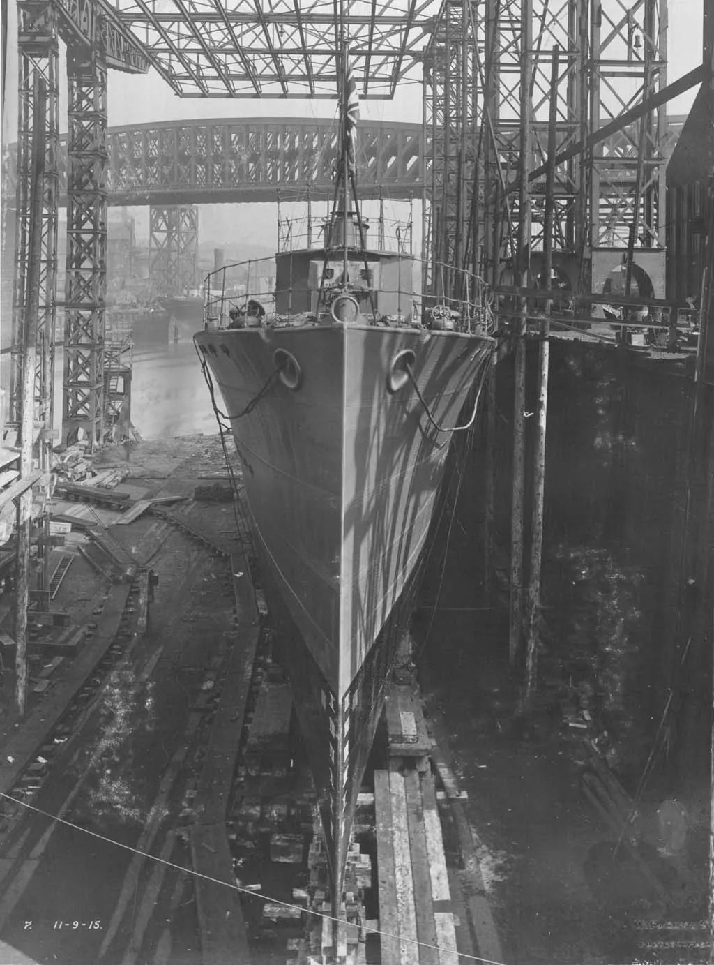 The sharp bow of the destroyer HMS Opal towers over the slipway at Doxford's yard, ready for launch under a steel gantry.